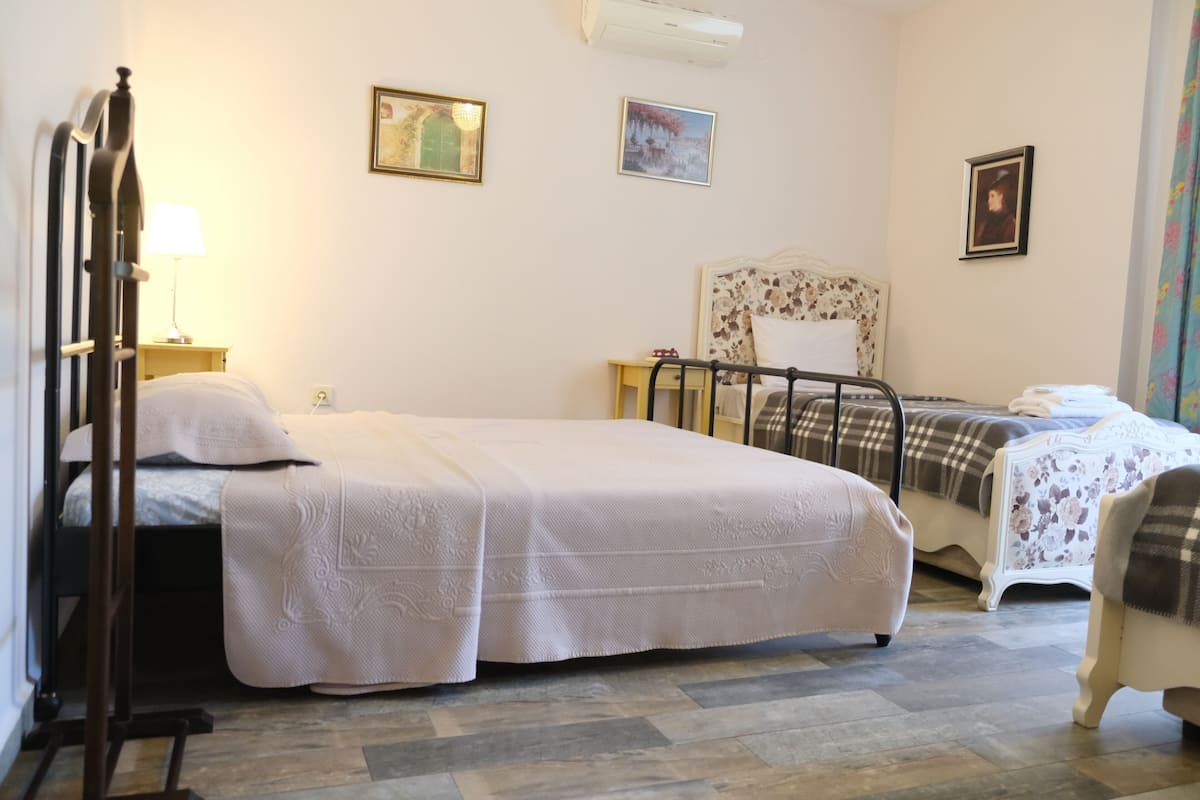 A bedroom with a large bed, a smaller bed, a chair, a nightstand, and a lamp.
