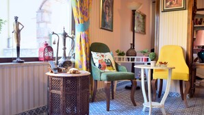 A room with a patterned floor, a green armchair, a yellow chair, a small round table, and a decorative lamp. - Nilufer Otel - Adult Only (Ayvalik)