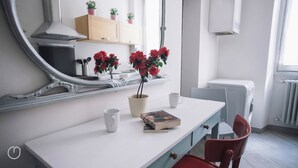 A modern kitchen with a white countertop, a mirror, a potted plant, a book, and a red chair. - Italianway   - C.so Sempione 96 (Milan)
