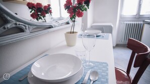 A dining table set with plates, cutlery, and a vase of red flowers. - Italianway   - C.so Sempione 96 (Milan)