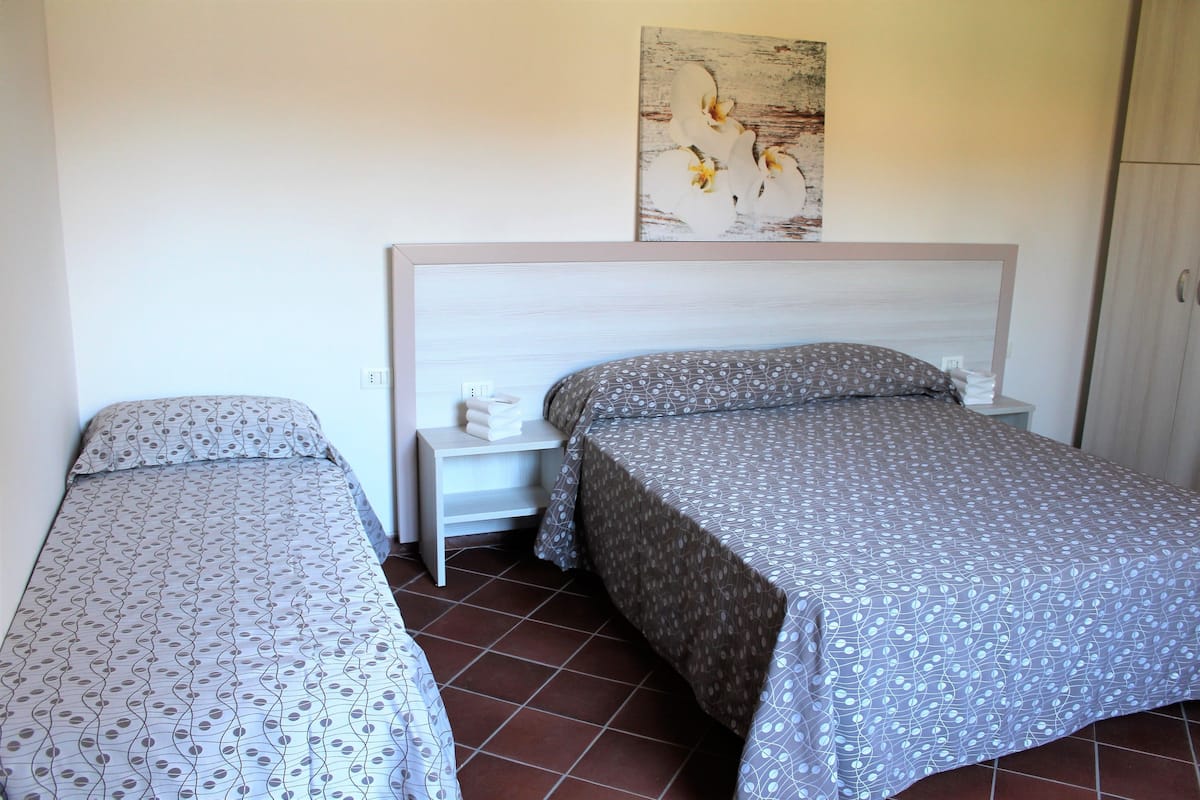 A bedroom with two beds, a nightstand, a painting, and a wardrobe.