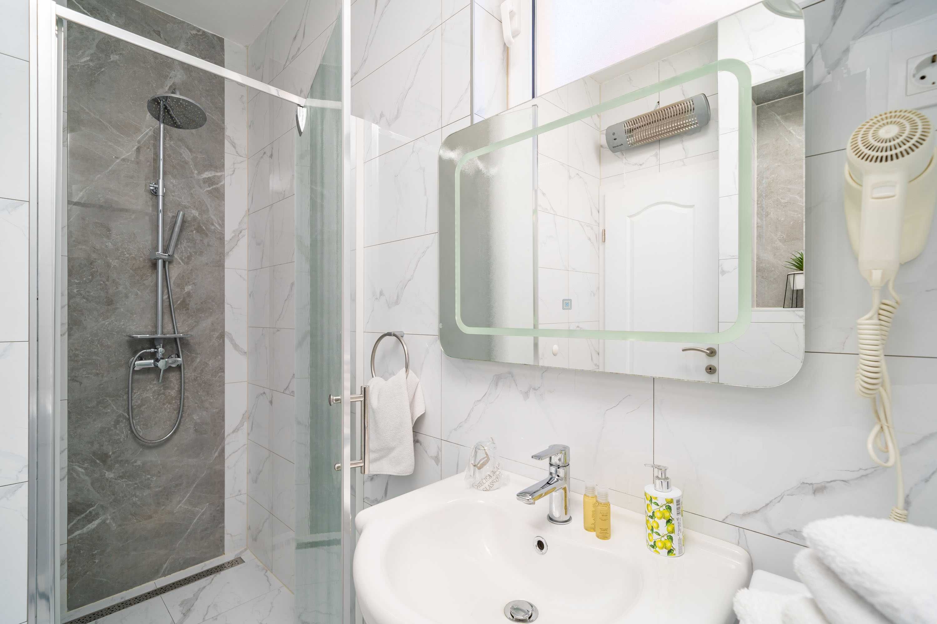 A bathroom with a shower, sink, and hairdryer.