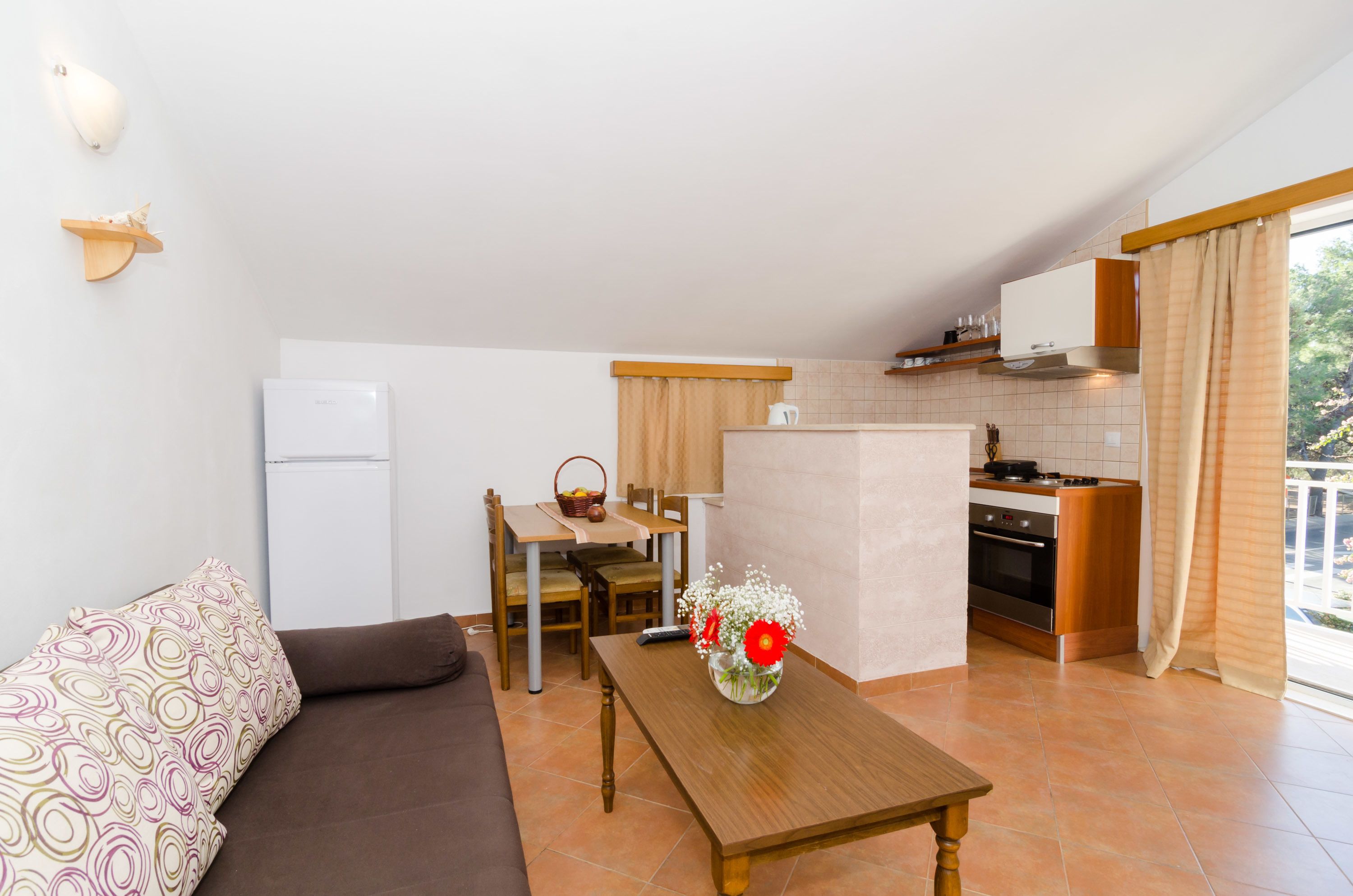 Un espacio habitable compacto con kitchenette, comedor y sofá.