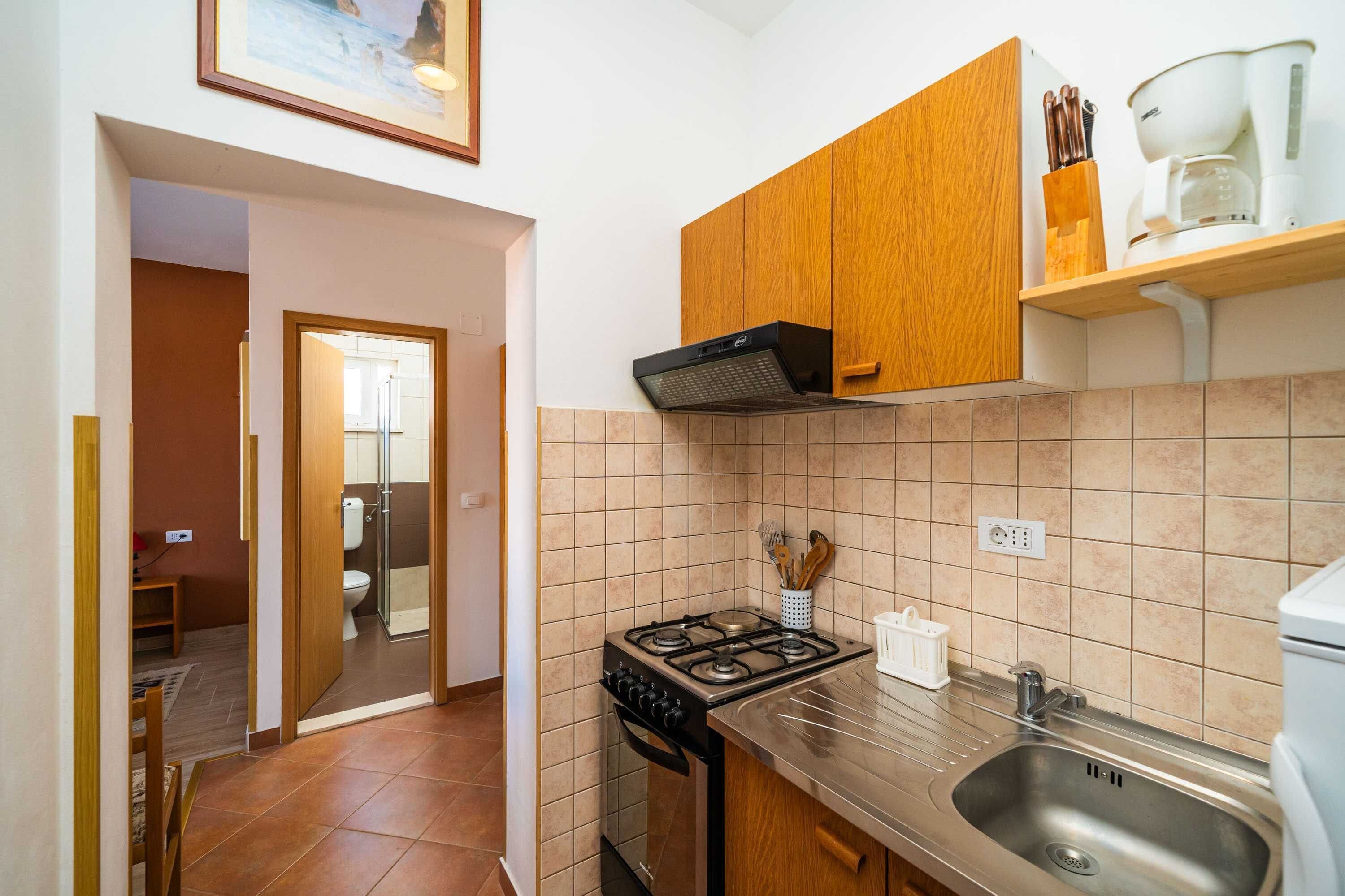 A kitchen with a gas stove, a sink, wooden cabinets, and a coffee maker.