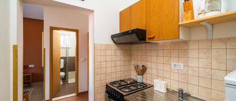 A kitchen with a gas stove, a sink, wooden cabinets, and a coffee maker.