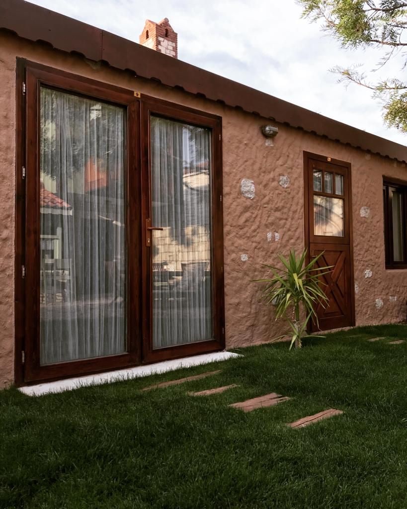 Un edificio con grandes puertas correderas de vidrio, fachada de piedra y un pequeño jardín.