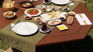Een eettafel buiten gedekt met verschillende gerechten en een menukaart.