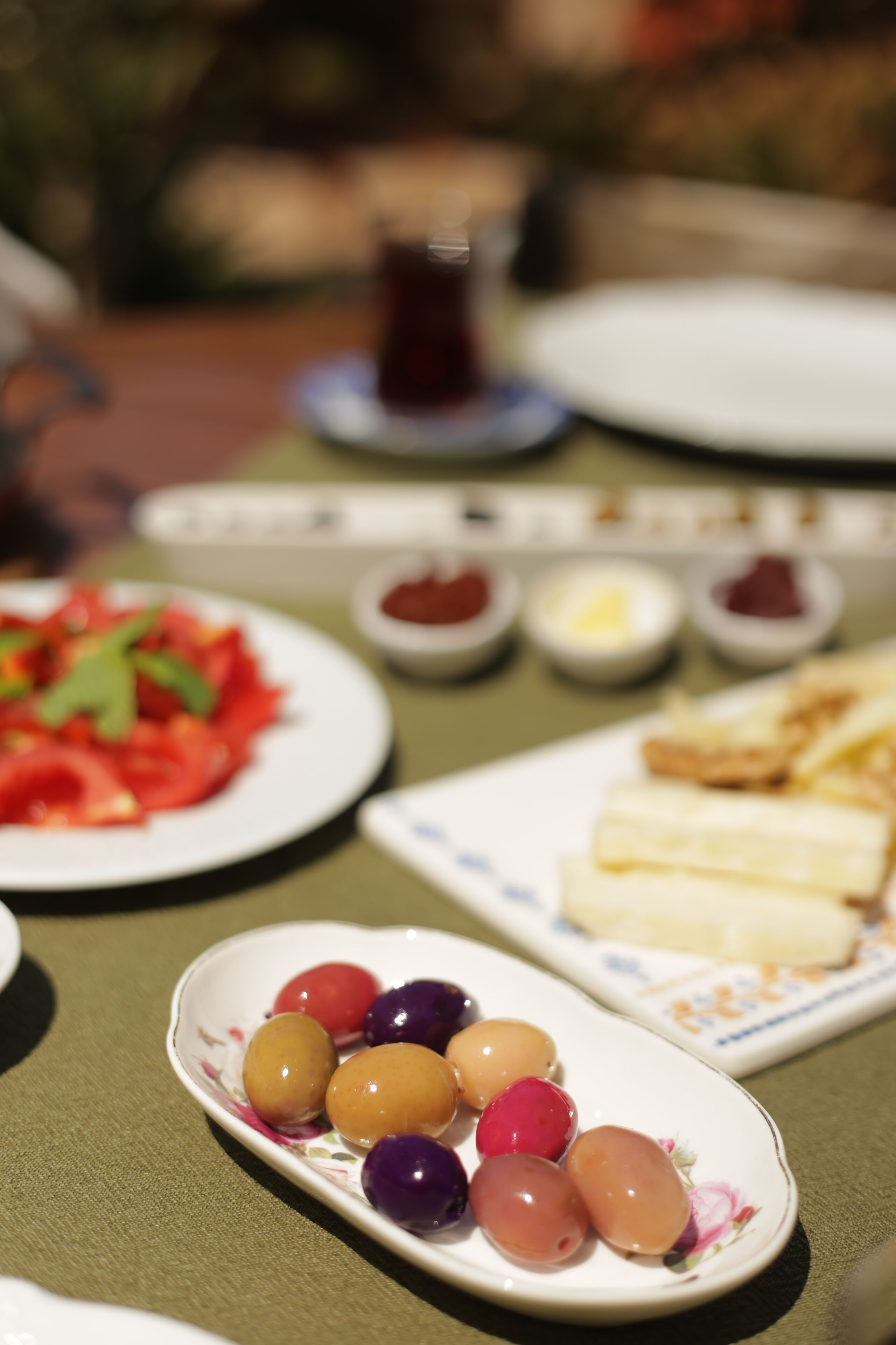 Una mesa con platos de comida, incluyendo una ensalada, queso y aceitunas.