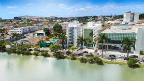 Un hotel con fachada de vidrio moderna, una terraza en la azotea y vistas del área urbana circundante.