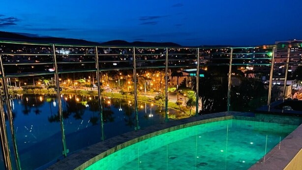 Una piscina infinita al aire libre con vistas a un paisaje urbano nocturno.