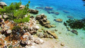 Un littoral rocheux bordé d’une eau d’un bleu limpide et d’une végétation verdoyante.