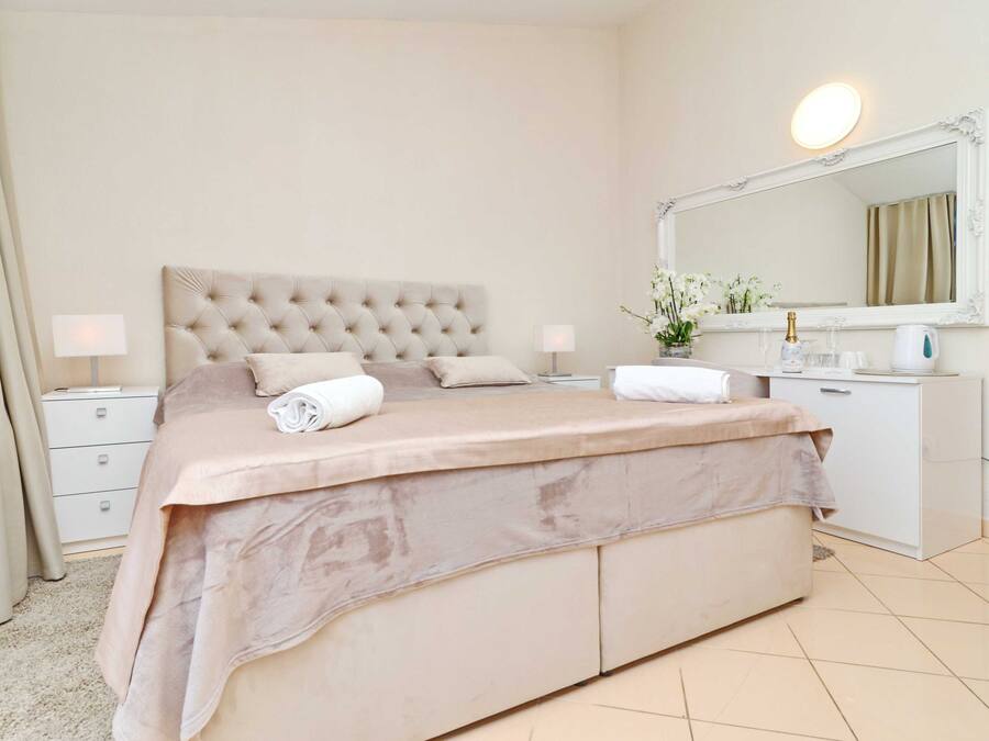 Ein Schlafzimmer mit einem großen Bett, einem Nachttisch, einer Kommode, einem Spiegel und einer Lampe.