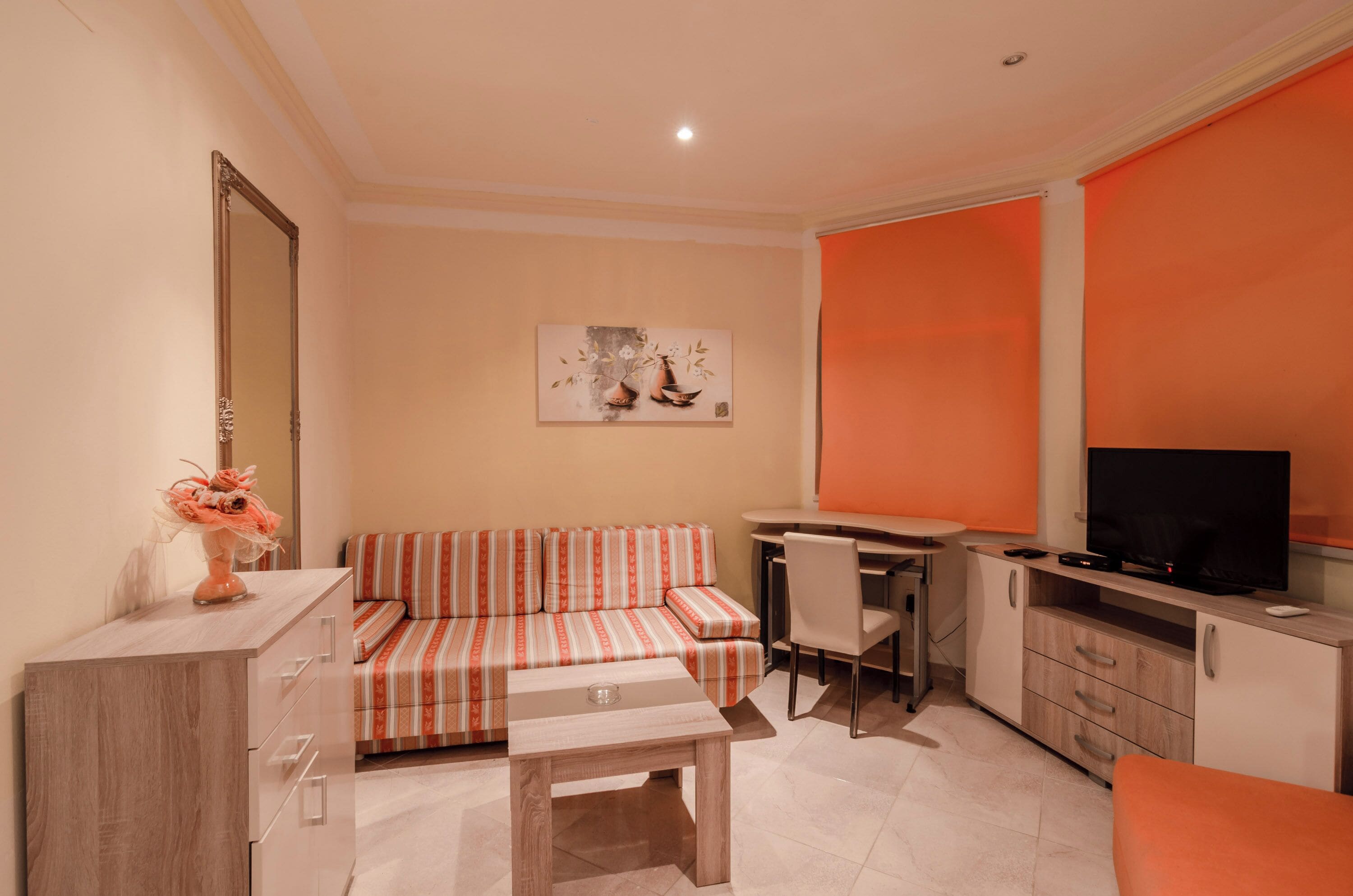 A compact living space with a sofa, a dining table, a TV, and a cabinet.