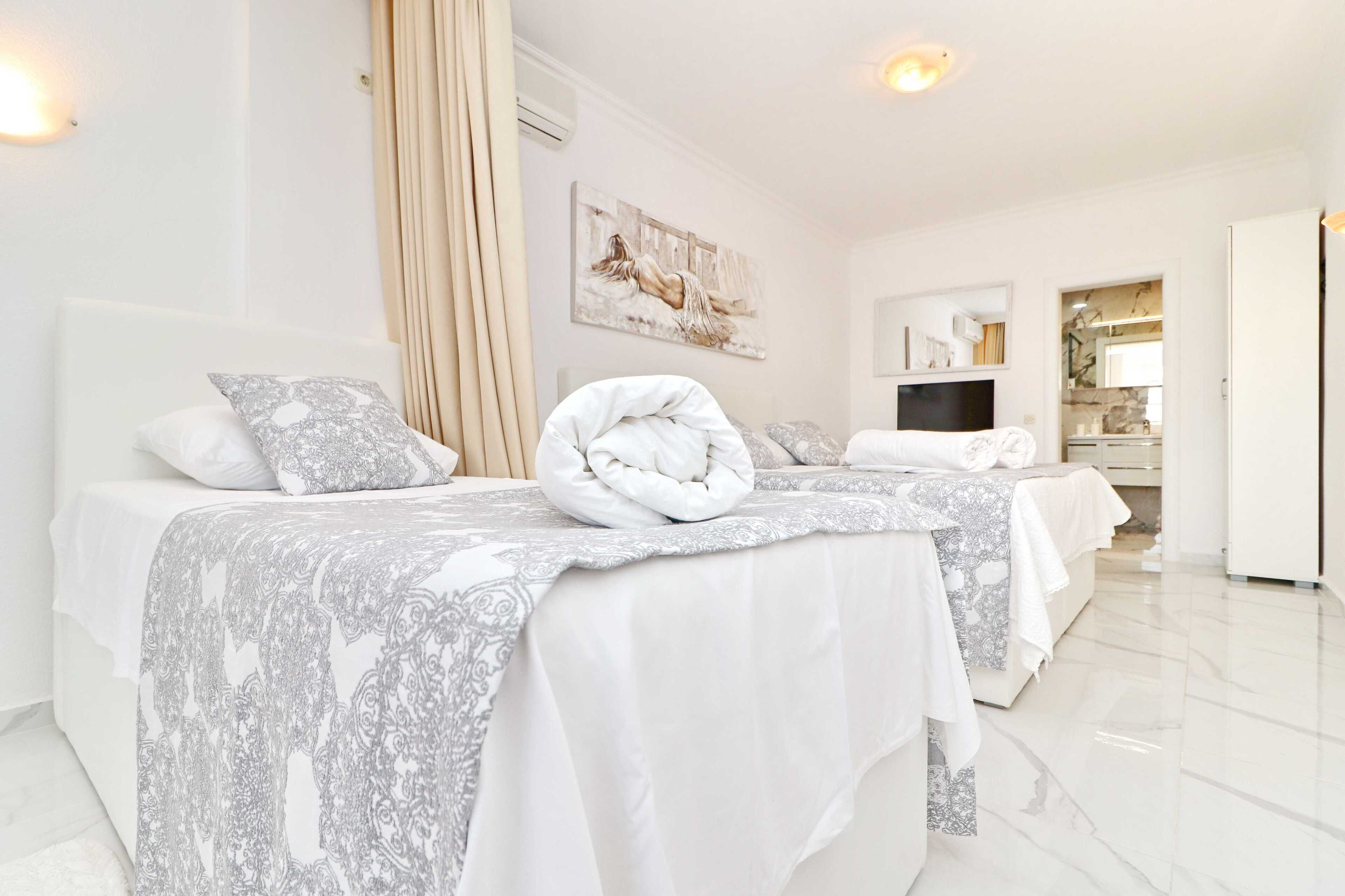 Une chambre d’hôtel avec deux lits, une grande fenêtre, un téléviseur à écran plat et une salle de bain visible par une porte ouverte.
