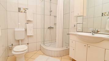 A modern bathroom with a toilet, a shower enclosure, a sink, and a mirror.
