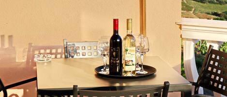 Una mesa servida con botellas de vino y copas, con vistas a un paisaje pintoresco.