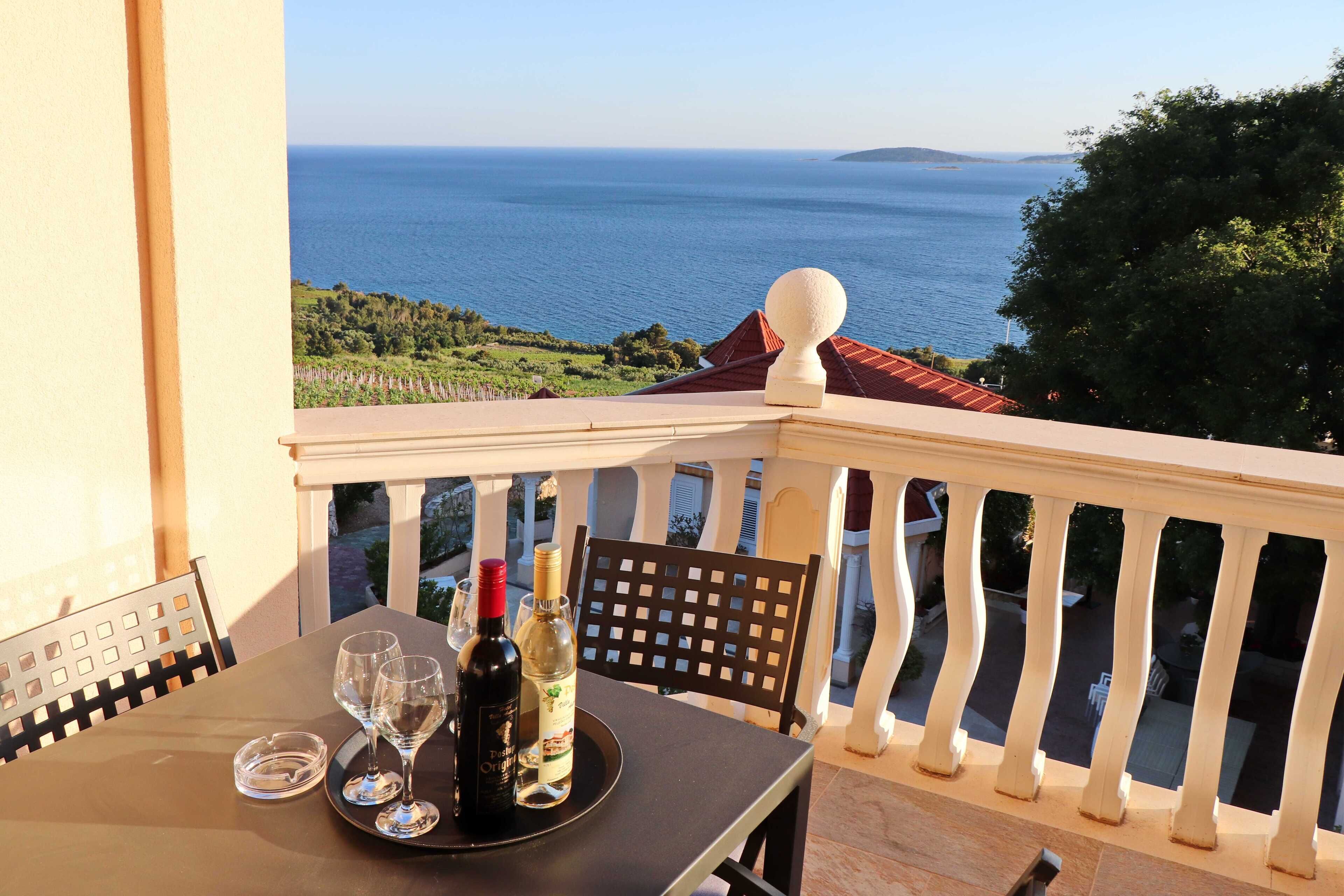 Un balcon avec une table dressée pour deux personnes, offrant une vue sur la côte.