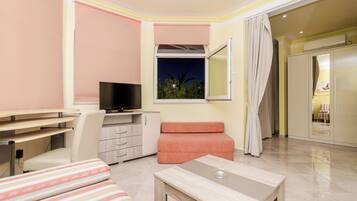 Ein modernes Hotelzimmer mit Flachbildfernseher, Schreibtisch, einer gepolsterten Sitzecke und Blick auf den Nachthimmel durch ein Fenster.