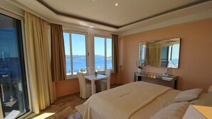 Une chambre d’hôtel avec un grand lit, un bureau et une vue sur la mer.