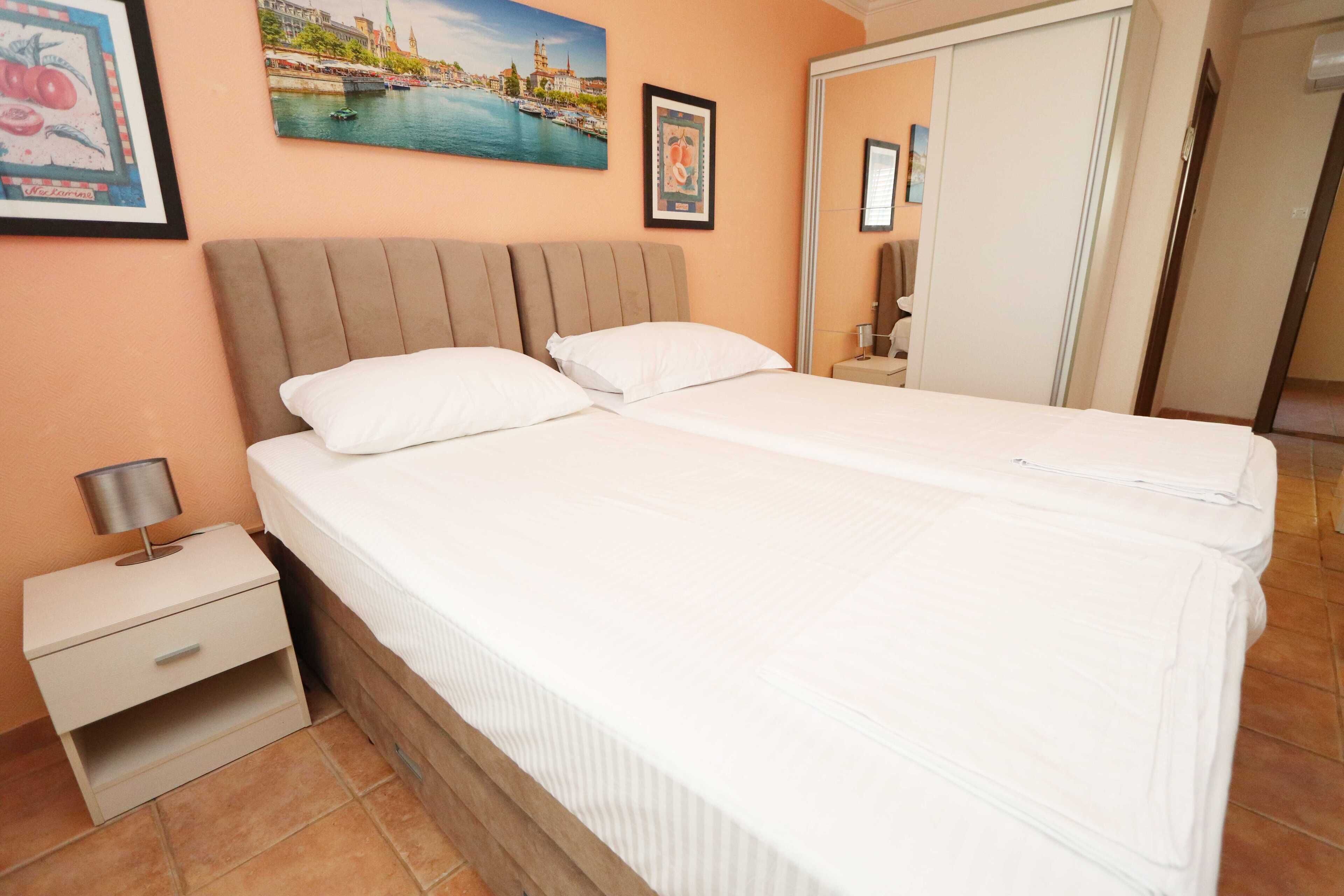 A hotel room with a bed, a nightstand, a mirror, and a door.
