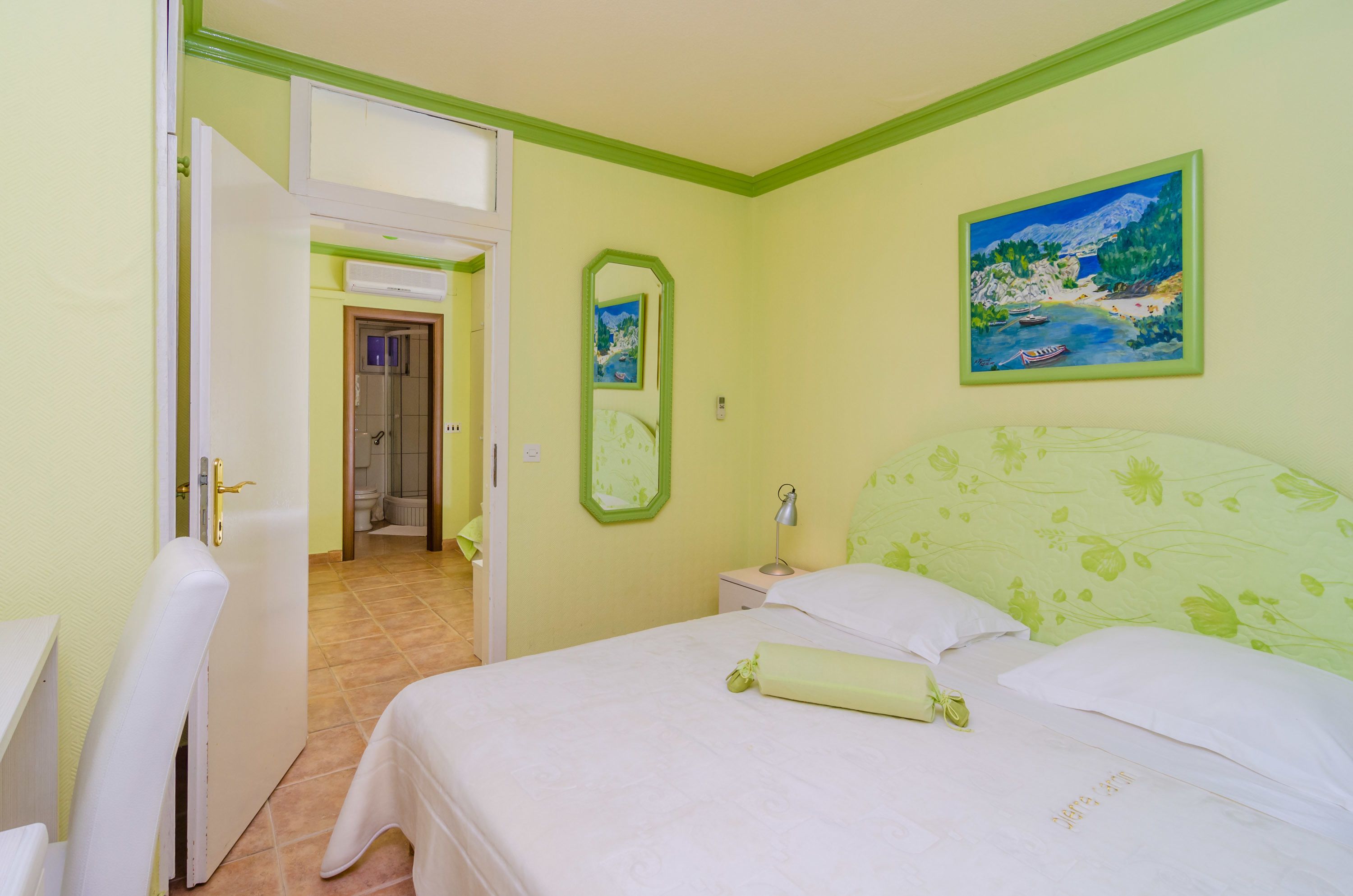 A hotel room with a bed, a bedside table, a lamp, and a painting on the wall.