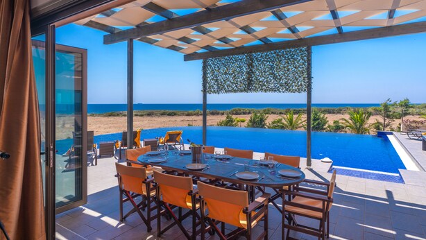 A dining area with a view of the ocean, a pool, and a beach. - Skinos ilivatos Boutique Eco Villa (Kefalonia)