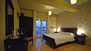 A hotel room with a bed, a chair, a desk, and a view of the outside.