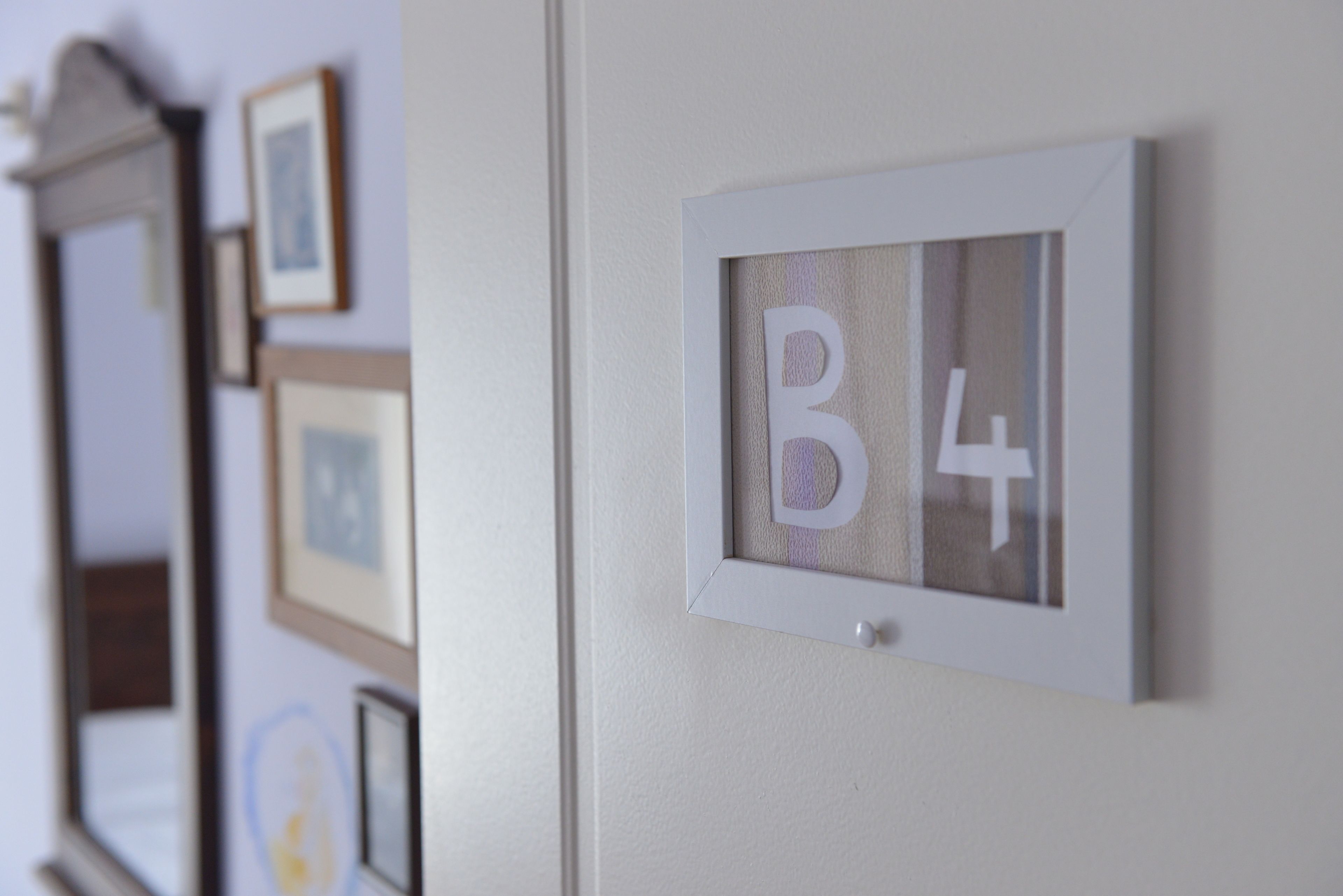 Una pared con letras enmarcadas 'B4' y varias fotografías enmarcadas.