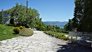 A stone pathway leading to a house with a view of mountains and a lake.