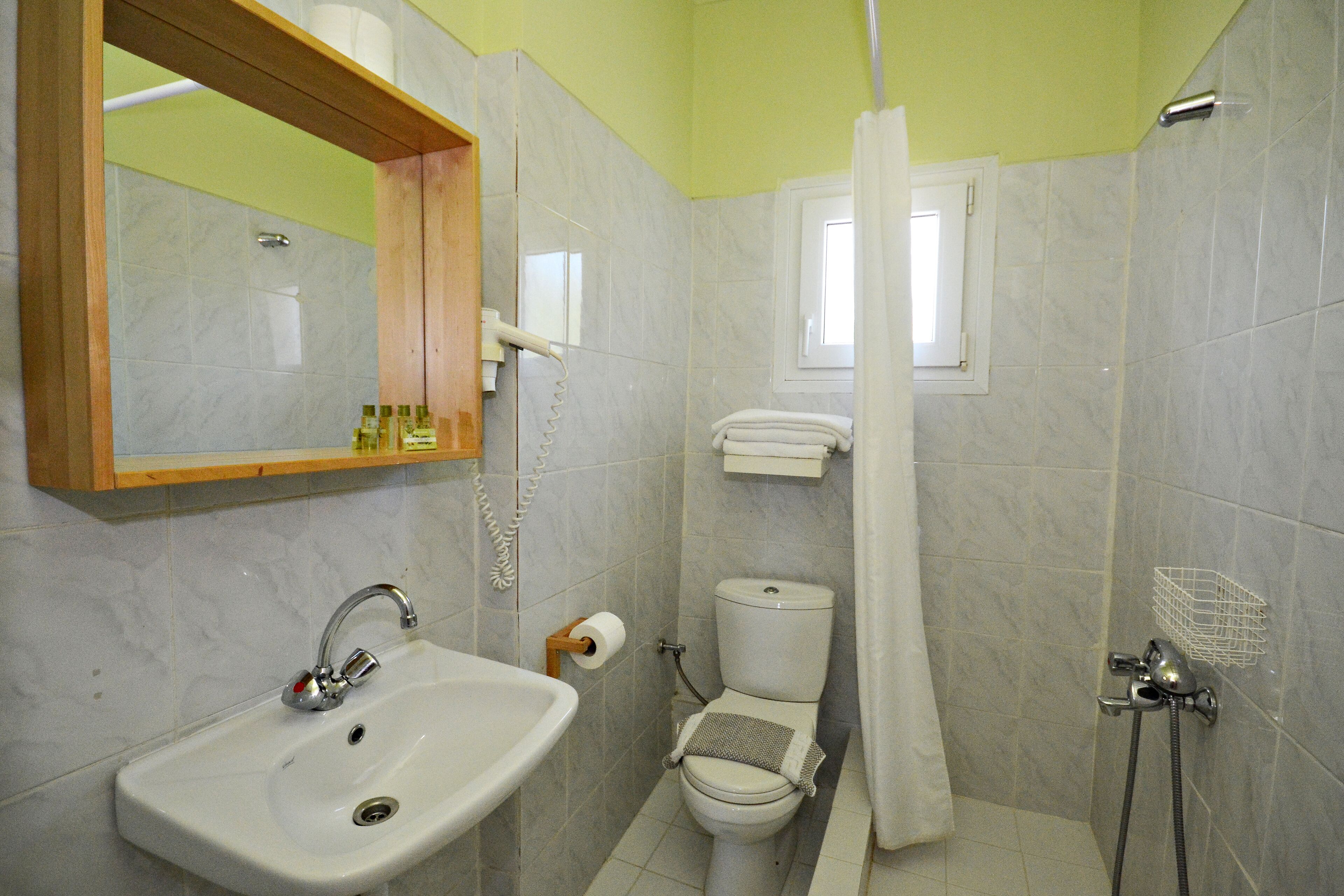 Ein Badezimmer mit Waschbecken, Toilette, Dusche und einem Fenster.
