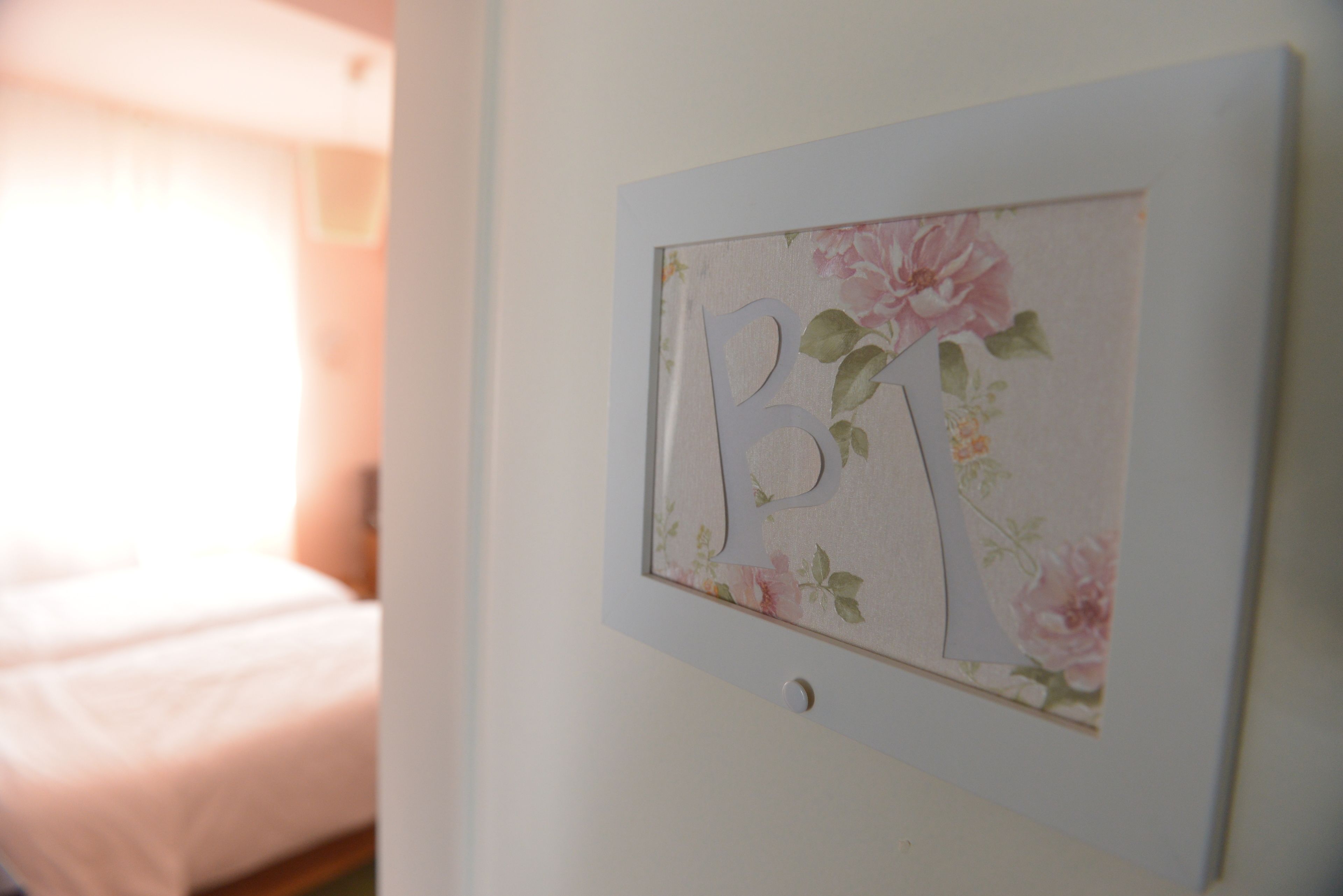 Ein gerahmtes Kunstwerk mit floralen Mustern und den Buchstaben "B1" an einer Wand.