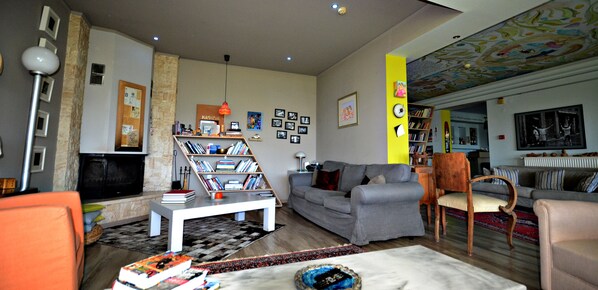 Un salon avec un canapé gris, une table basse blanche, une bibliothèque et une cheminée.