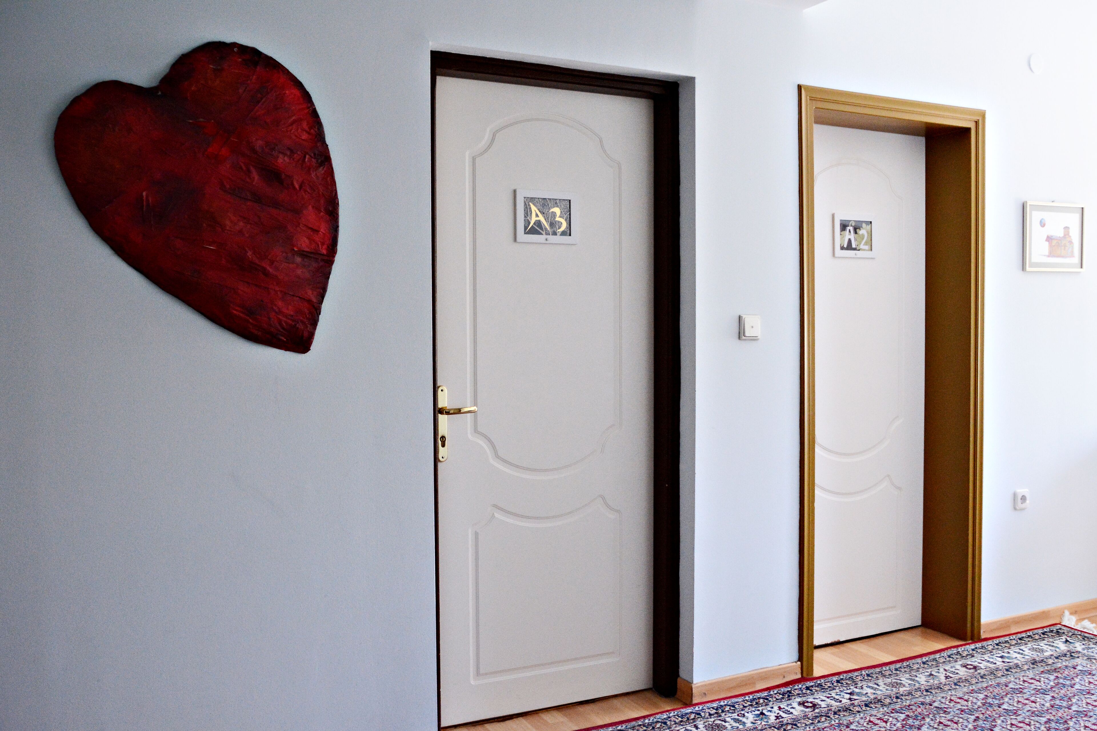 Un pasillo con dos puertas, una decorada con un corazón y la otra con una pequeña imagen.