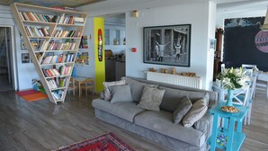 A living room with a grey sofa, a bookshelf, a red rug, and a framed picture on the wall.