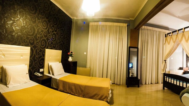 Una habitación de hotel con cama, una silla, escritorio, televisor y baño.