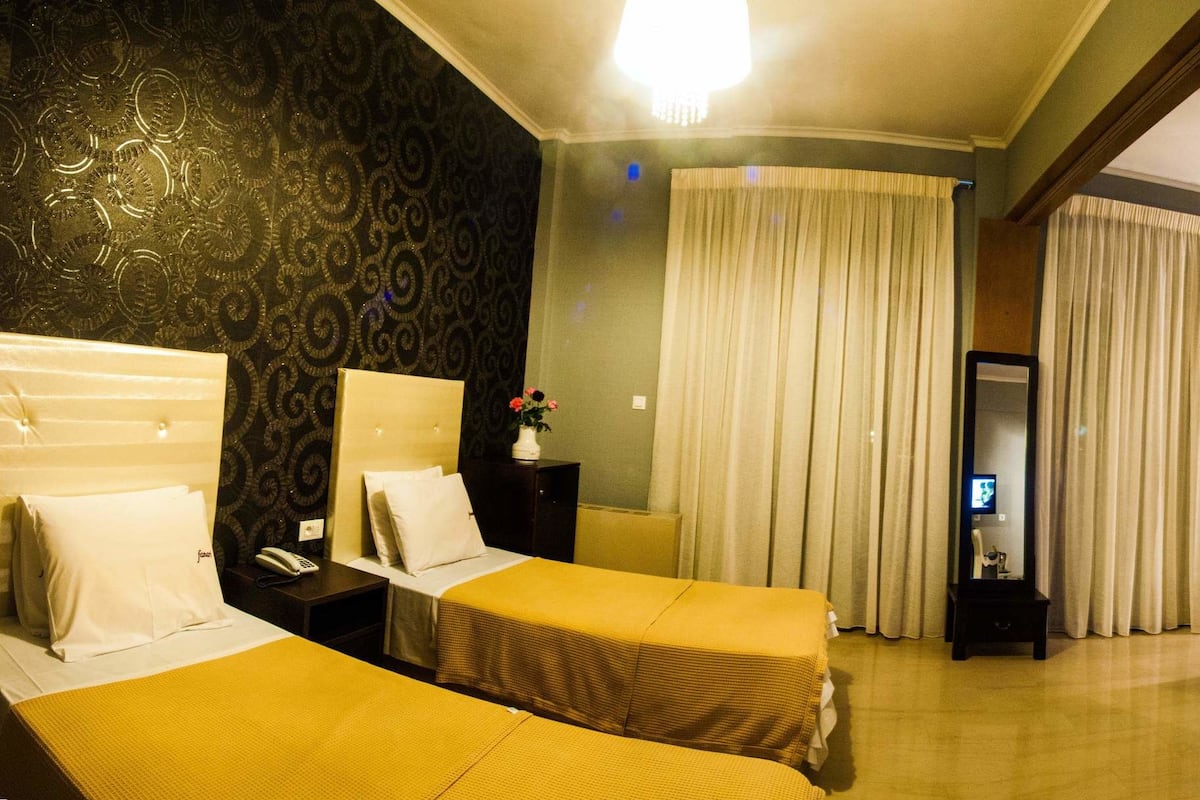 A hotel room with a bed, a chair, a desk, a TV, and a bathroom.