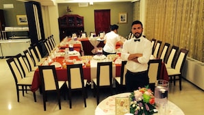 Un comedor formal con una larga mesa dispuesta para una comida, rodeada de sillas.