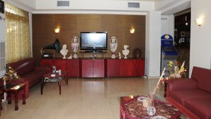 Una sala de estar con televisor, sofás rojos, una mesa de centro y jarrones decorativos.