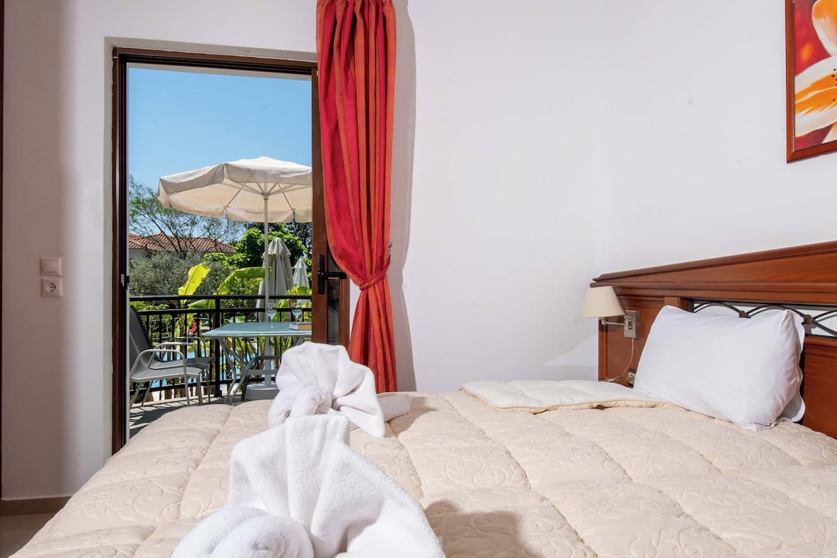 Ein Hotelzimmer mit Bett, einem Balkon und Gartenmöbeln sowie einem roten Vorhang.