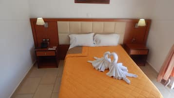 Habitación de hotel con una cama grande, dos mesitas de noche, un cuadro en la pared y una escultura de toallas en la cama.