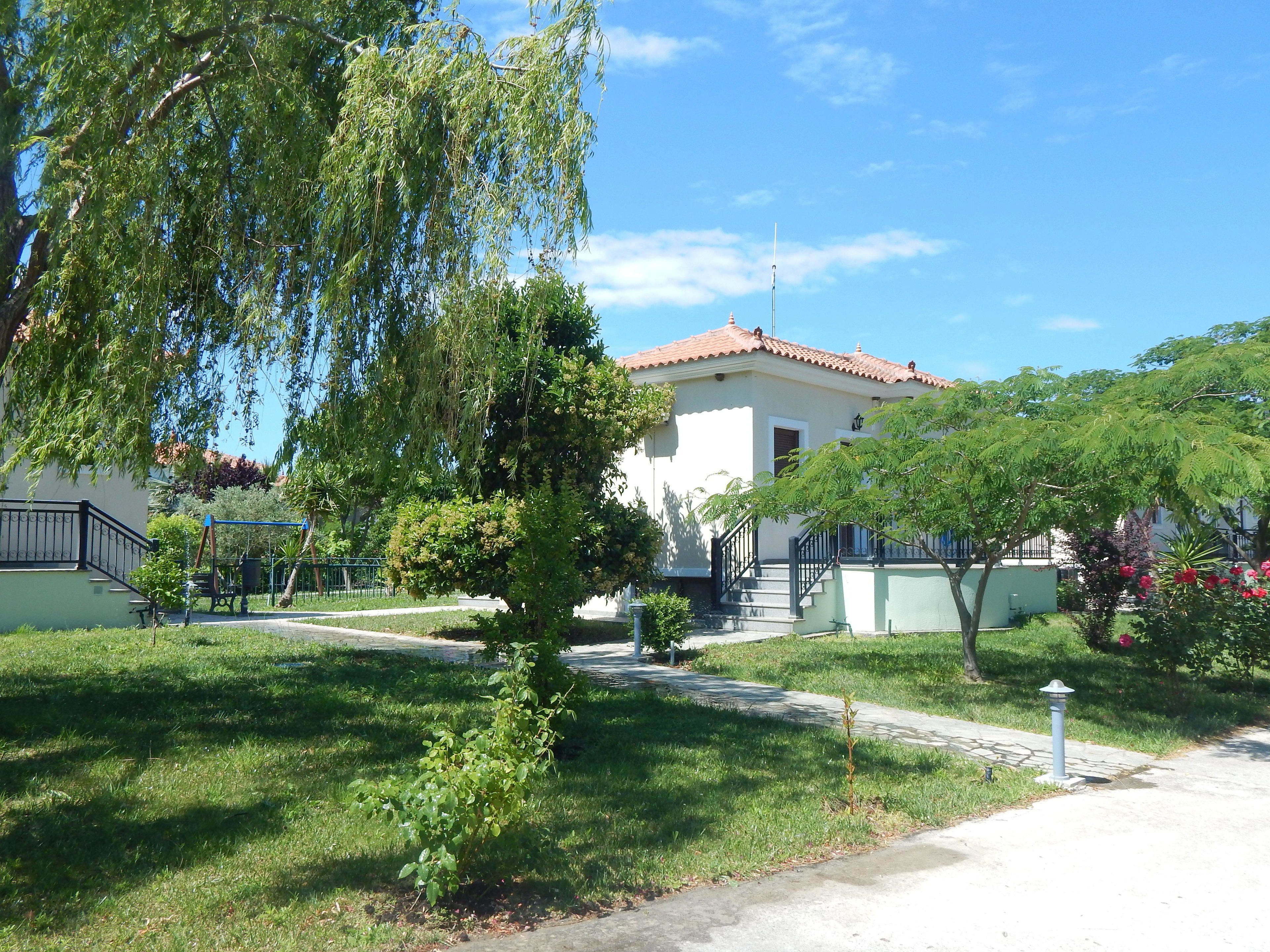 A residential building with a tiled roof, a visible staircase, and a well-maintained lawn.