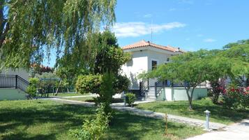 A residential building with a tiled roof, a visible staircase, and a well-maintained lawn.