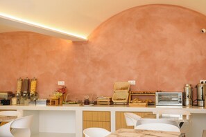A modern kitchen with a curved wall, a built-in oven, and a variety of food items and condiments on the counter.