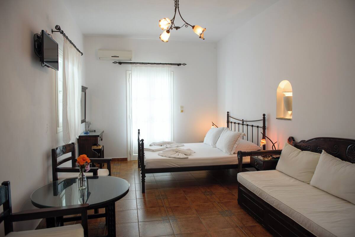 A bedroom with a bed, bedside table, lamp, and a small table with a vase.