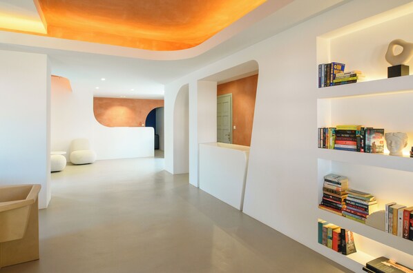 A modern interior with a reception desk, white sofas, and bookshelves.