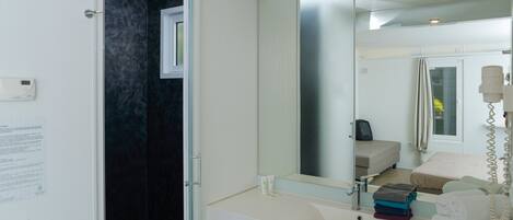 A modern bathroom with a large mirror, a white sink, and a towel rack.