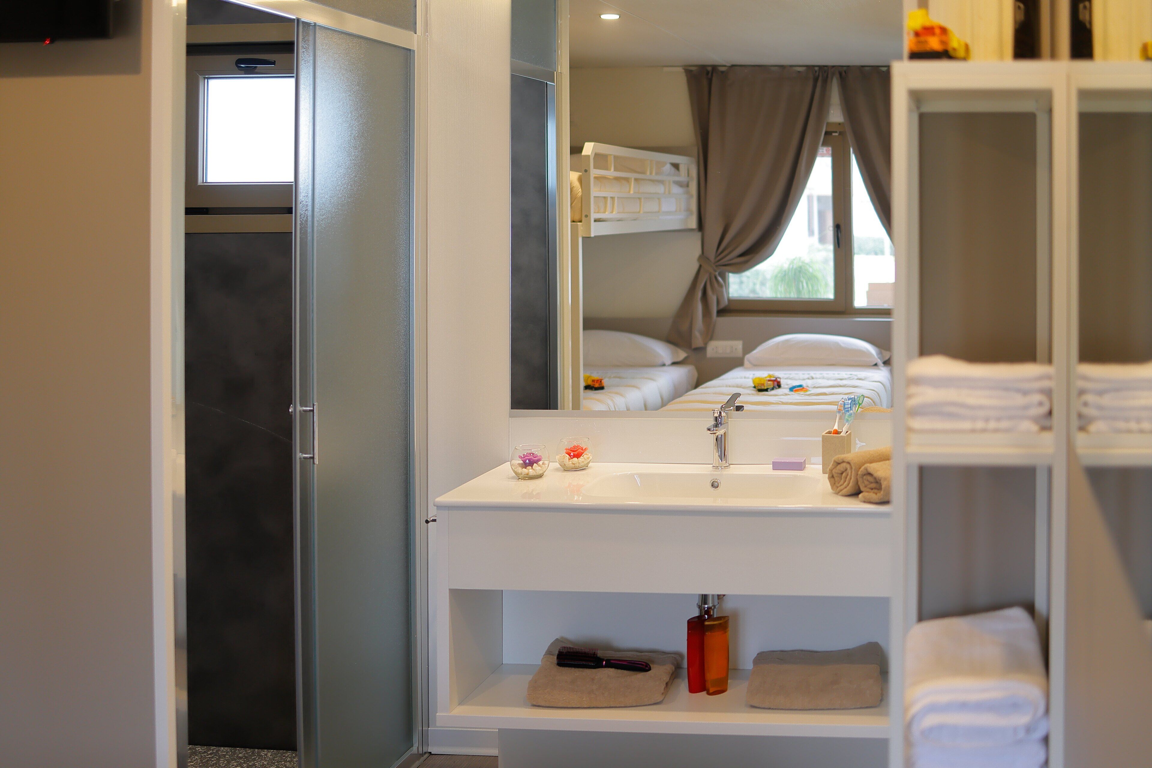 A hotel bathroom with a white sink, mirror, and a shower area.