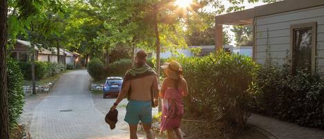 A couple walking on a paved path in a residential area with houses and greenery.