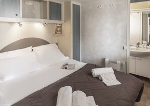 Une chambre d’hôtel comprenant un lit, une table de chevet, un radiateur, un miroir et une salle de bain avec un lavabo.