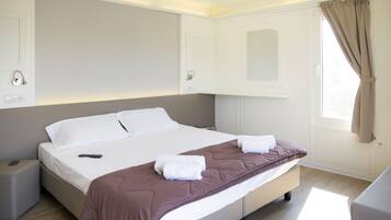 Ein modernes Hotelzimmer mit einem großen Bett, Nachttischen, einem Vorhangfenster und integrierten Stauraumschränken.